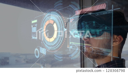 Wearing VR headset, man interacting with futuristic digital interface over architectural designs Wearing VR headset, man interacting with futuristic digital interface over architectural designs 128308798