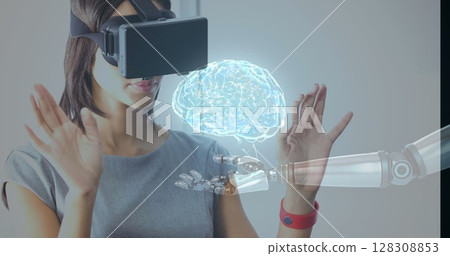 Using virtual reality headset, woman interacting with robotic hand and holographic brain Using virtual reality headset, woman interacting with robotic hand and holographic brain 128308853