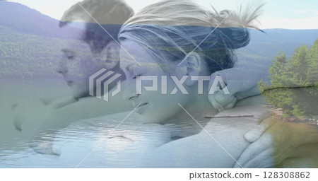 Digital composite of couple enjoying a relaxing back massage, with peaceful lake surrounded by green 128308862