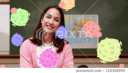 Image of Covid 19 text and coronavirus cells spreading over smiling female teacher and pupils in cla 128308949