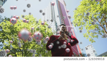 Man in red sweater holding coffee, talking on phone, surrounded by virus particles 128309018