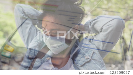 Woman wearing mask adjusting hair, reflecting on pandemic challenges outdoors 128309037
