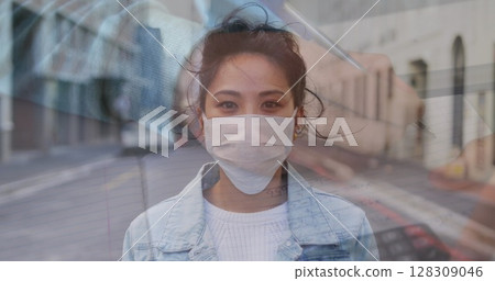 Woman wearing face mask standing on street, looking serious during pandemic 128309046