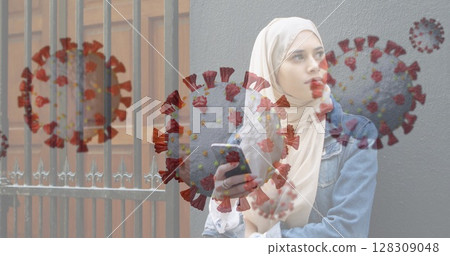 Holding smartphone, Muslim woman outdoors with coronavirus graphics overlay Holding smartphone, Muslim woman outdoors with coronavirus graphics overlay 128309048