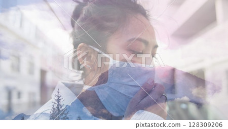 Image of woman wearing face mask against winter scenery 128309206