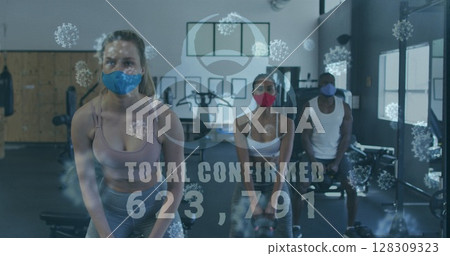 Image of covid-19 cells floating over diverse group wearing face masks working out 128309323