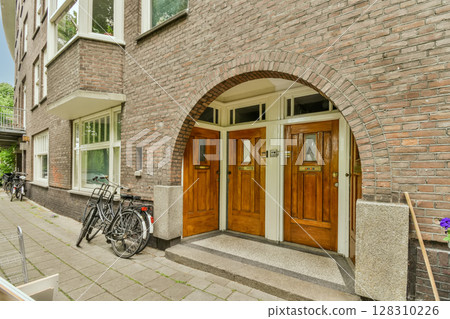 a brick building with two bikes parked in the doorways and one bike leaning against the wall on the other side 128310226