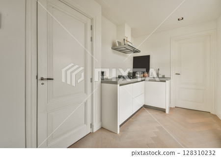 a kitchen with white cabinets and black appliances on the wall above it is an open door that leads to another room 128310232