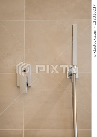 a shower head and hand rail in a tiled bathroom photo taken from the side, with focus to the wall stock photo 128310237