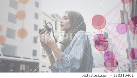 Image of a network of pink and red icons with woman wearing hijab taking photos in street 128310401