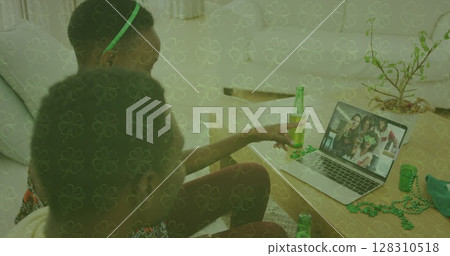 Image of clover over couple celebrating st patrick's day with friends on laptop image call 128310518
