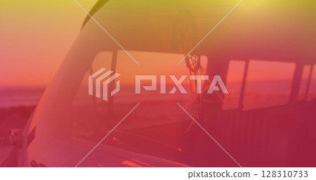 Image of dream catcher moving in camper van with yellow to red hue with sunset in background 128310733