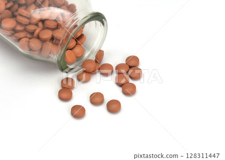 Pile of pills in a bottle on white background 128311447
