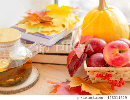 Cozy autumn, books, tea and apples on the windowsill with autumn fallen leaves 128311829