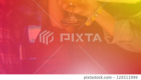 Image of people having drinks at party and dancing on red to yellow tinted background 128311999