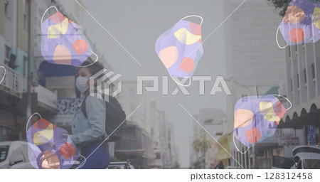 Multiple face masks moving against woman wearing face mask with bicycle crossing the street 128312458