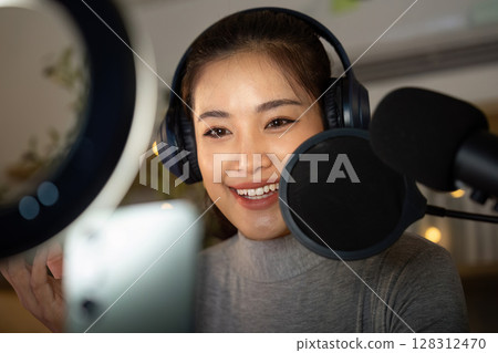 Podcast recording session with enthusiastic host engaging with audience 128312470