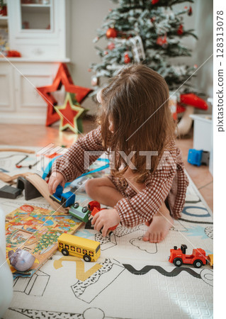 Child Playing with Toy Trains Near Christmas Tree 128313078