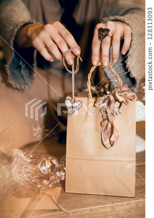 Woman Wrapping Christmas Gift with Brown Paper Bag 128313093