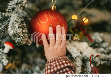 Child Touching Christmas Ornament on Tree Branch Child Touching Christmas Ornament on Tree Branch 128313100
