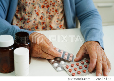Asian elderly woman holding pill drug with water in glass, strong healthy medical. 128313188