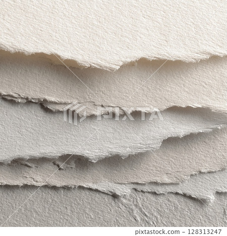 Close-up shot of layered, torn paper edges with a soft, textured appearance. 128313247