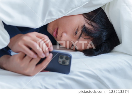 男人在床上使用智慧型手機 128313274