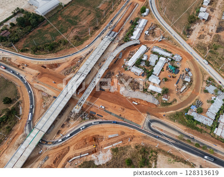 The construction site before the construction of the concrete bridge over the intersection by crane workers, tractors, and backhoes The construction site before the construction of the concrete bridge over the intersection by crane workers, tractors, and backhoes 128313619