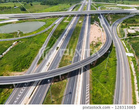 Drone shot a large highway interchange crossing over green farmlands in Thailand 128313865