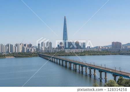 Beautiful view of modern tower and Jamsil Railway Bridge over the Han River (Hangang) at downtown of Seoul in South Korea. Scenic skyscraper is visible on blue sky background. Wonderful cityscape. 128314258