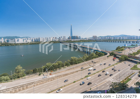 Beautiful view of modern tower and Jamsil Railway Bridge over the Han River (Hangang) at downtown of Seoul in South Korea. Scenic skyscraper is visible on blue sky background. Wonderful cityscape. 128314279