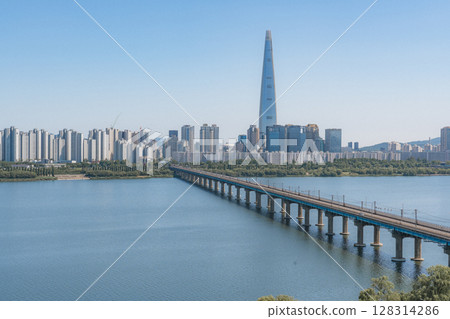 Beautiful view of modern tower and Jamsil Railway Bridge over the Han River (Hangang) at downtown of Seoul in South Korea. Scenic skyscraper is visible on blue sky background. Wonderful cityscape. 128314286