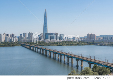 Beautiful view of modern tower and Jamsil Railway Bridge over the Han River (Hangang) at downtown of Seoul in South Korea. Scenic skyscraper is visible on blue sky background. Wonderful cityscape. 128314288