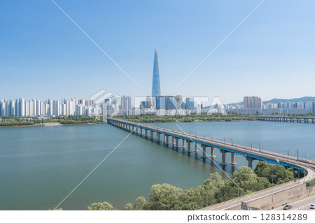 Beautiful view of modern tower and Jamsil Railway Bridge over the Han River (Hangang) at downtown of Seoul in South Korea. Scenic skyscraper is visible on blue sky background. Wonderful cityscape. 128314289