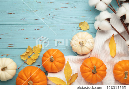Beautiful mini pumpkins with autumn leaves on blue background Beautiful mini pumpkins with autumn leaves on blue background 128315565