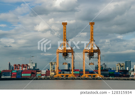 Industrial cranes on a waterfront, facilitating shipping and transportation in a bustling port environment. Industrial cranes on a waterfront, facilitating shipping and transportation in a bustling port environment. 128315934