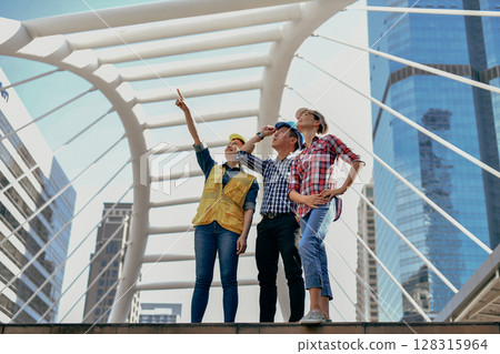 Three friends enjoying a city exploration, pointing out landmarks with excitement and camaraderie. 128315964