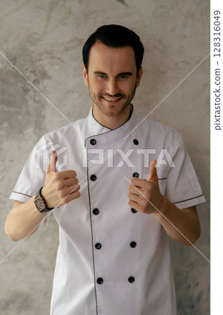 A cheerful chef giving a thumbs up in a professional kitchen, representing culinary excellence and positive vibes. 128316049