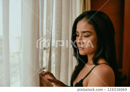 A contemplative woman gazing out the window, creating a serene atmosphere of reflection and introspection. 128316069