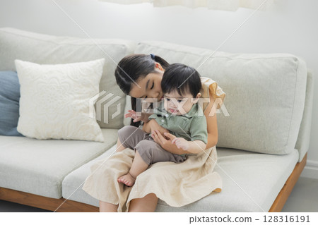 Older sister hugging her younger brother 128316191