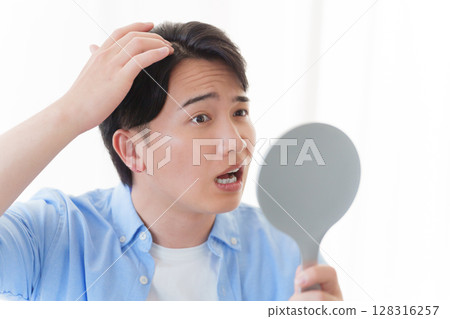 男人對著鏡子檢查自己的頭髮 128316257