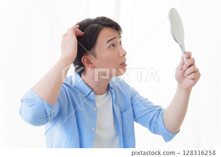 男人對著鏡子檢查自己的頭髮 128316258