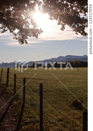 A fence separates a field from a mountain range 128317059