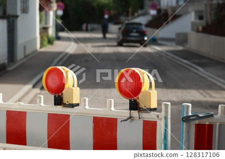 Red and white striped barrier with two red lights on top 128317106