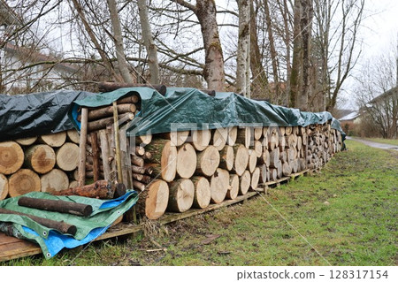 A pile of wood logs covered with plastic tarps A pile of wood logs covered with plastic tarps 128317154
