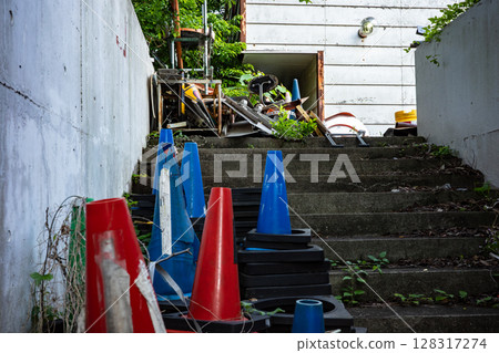 Pylons and other items are left abandoned on the stairs at the back of the building. 128317274