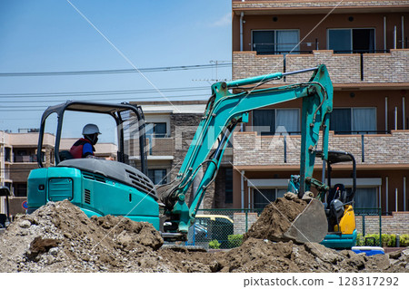 A worker using a small excavator to develop a residential area 128317292