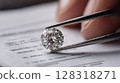 Close-up of a sparkling round diamond being held with tweezers above a document, showcasing intricate details 128318271