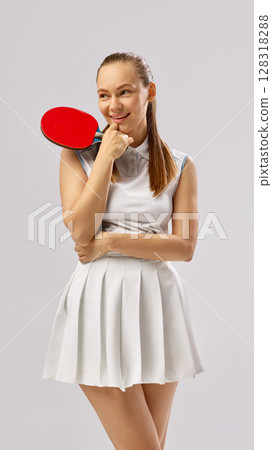 Young woman posing with table tennis paddle in white attire Young woman posing with table tennis paddle in white attire 128318288