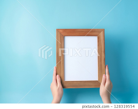 Woman's hands holding a wooden frame 128319554
